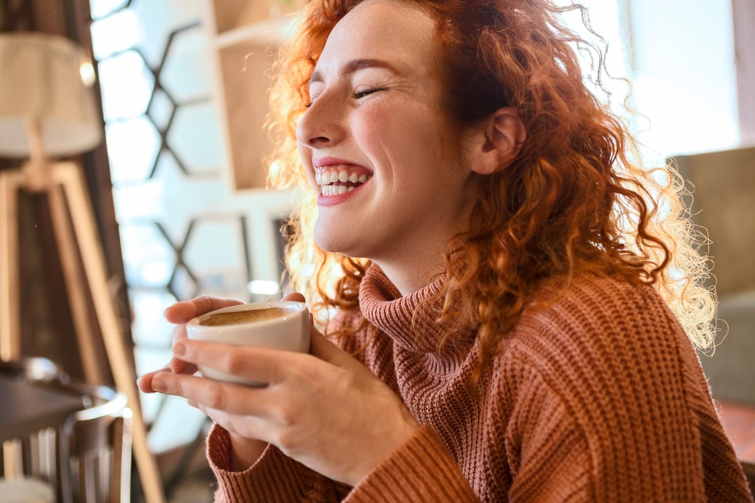 Young redhead woman drinking coffee smiling